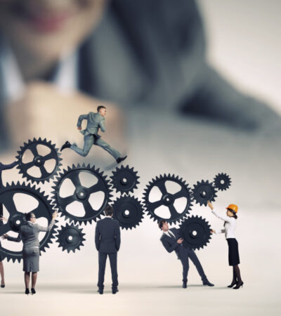 Businesswoman looking at team of businesspeople in miniature